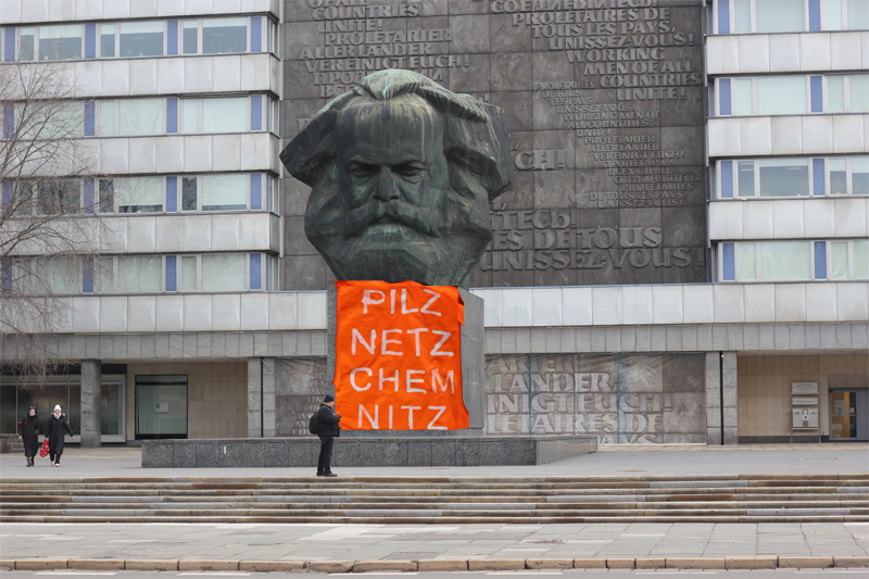 Karl-Marx-Skulptur in Chemnitz, davor Warnweste mit Aufschrift: Pilznetz Chemnitz (Kirsten Kötter)